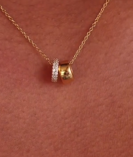 Gold and silver beaded necklace on a person's neck against a pink background